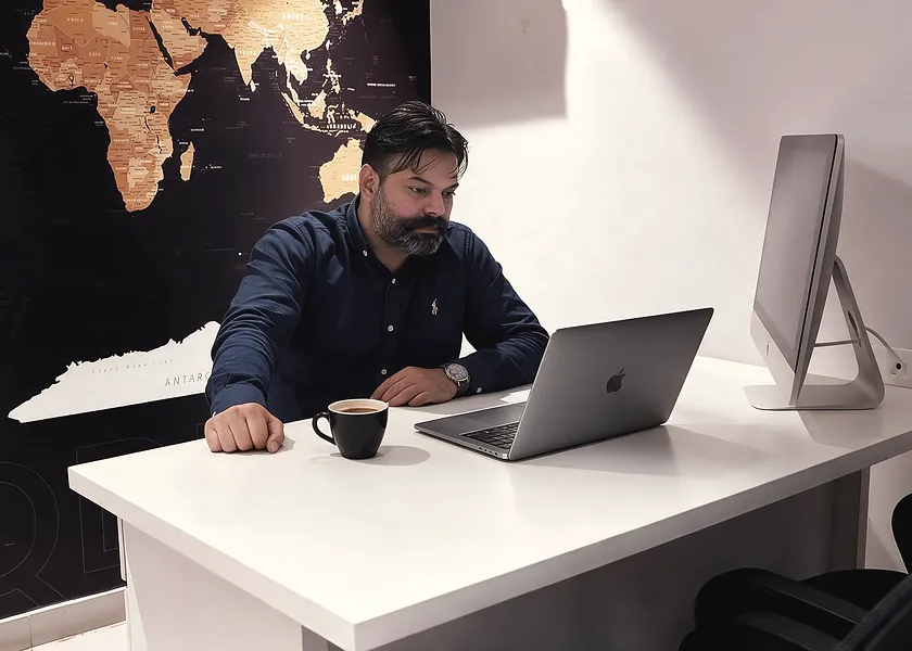 A colleague at a laptop in front of a world map