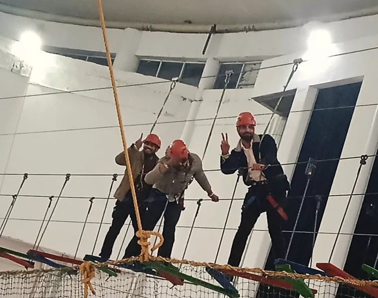 Two colleagues in helmets crossing a high rope course