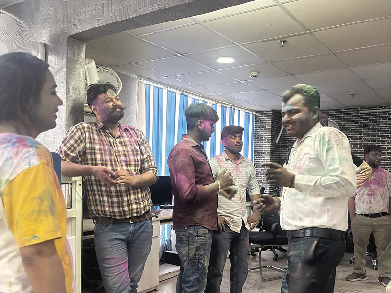 Colleagues talking in the office on Holi, colour on their shirts